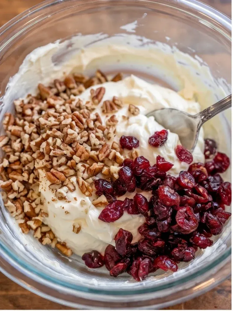 Mixing cream cheese with chopped pecans and dried cranberries for holiday skewer bites
